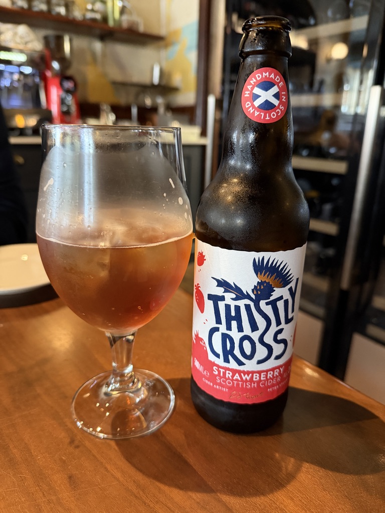 A bottle of Thistly Cross strawberry cider beside a full glass at The Ship on the Shore in Leith.