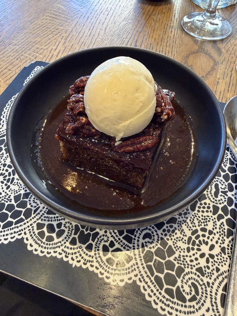 Sticky toffee pudding topped with pecans and vanilla ice cream at The Scran and Scrallie in Stockbridge, Edinburgh.